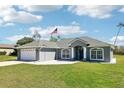 Beautifully landscaped single-story home with a neat lawn and a view of the two-car garage at 10367 Sw 45Th Ave, Ocala, FL 34476