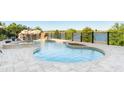 Backyard oasis with a luxurious pool featuring a rock waterfall and tranquil views of the lake at 15681 Panther Lake Dr, Winter Garden, FL 34787