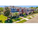Row of colorful two-story townhomes with lush landscaping, brick paved driveways, and well-manicured lawns at 16241 Old Ash Loop, Orlando, FL 32828