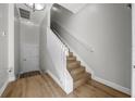 Bright hallway featuring hardwood floors and a staircase with white railing, leading to upper levels at 165 Rosette Dr, Winter Springs, FL 32708