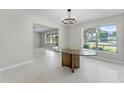 Elegant dining room featuring a glass-top table and modern chandelier with a view to the living room at 2178 Whitehall Dr, Winter Park, FL 32792