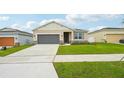 Charming single-story home with a two-car garage, complemented by lush green lawn and landscaping at 33332 Seattle Slew Dr, Sorrento, FL 32776