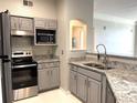Stylish kitchen with stainless steel appliances, granite countertops, gray cabinets, and a modern backsplash at 3384 Corona Village Way # 202, Orlando, FL 32835