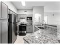 Modern kitchen featuring stainless steel appliances, granite countertops, and gray cabinetry at 3384 Corona Village Way # 202, Orlando, FL 32835