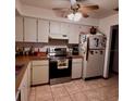 Bright kitchen with tile floor, updated stainless steel appliances, and fan with overhead lighting at 604 Tradewinds Dr, Deltona, FL 32738