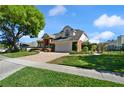 Side view of a two-story home with brick accents, a well-maintained lawn, and a brick driveway leading to the garage at 437 Wilmington Cir, Oviedo, FL 32765