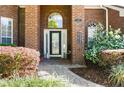 Close-up of a brick home's entrance with a decorative door, lush landscaping, and a charming wind chime at 437 Wilmington Cir, Oviedo, FL 32765