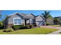 Well-kept single-story home featuring stone accents, a brick driveway, and lush landscaping at 1530 Lexington Av Ave, Davenport, FL 33837