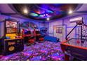 Fun-filled game room features arcade games, custom wall art, and vibrant lighting at 2320 Lelani Cir, Davenport, FL 33897