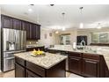 Open-concept kitchen with dark wood cabinetry, granite countertops, stainless appliances, and island with seating at 2731 Cypress Tree Trl, St Cloud, FL 34772
