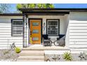 A cozy front porch with a modern orange door, seating, and stylish details enhance this home's entrance at 407 E Jersey St, Orlando, FL 32806