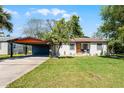 Inviting single-Gathering home with a vibrant orange door, lush green lawn, and convenient covered parking at 407 E Jersey St, Orlando, FL 32806