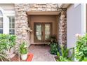Elegant double doors framed by stone, complemented by lush landscaping and a tiled entryway at 9054 Sandwood Way, Orlando, FL 32832