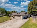 Single-story home with an attached garage and long driveway, featuring stone accents, landscaping, and a well-maintained lawn at 9501 Holbrook Dr, Orlando, FL 32817