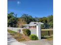 Gray single Gathering home with gray wall, black fence, lush trees, and blue sky at 1661 Votaw Rd, Apopka, FL 32703