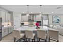 Bright, modern kitchen featuring a large island, pendant lighting, and stainless steel appliances at 19318 Banfield Pl, Orlando, FL 32827