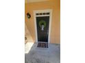 A close-up of a black front door decorated with a green wreath and featuring a 'HELLO' welcome mat at 3433 Soho St # 101, Orlando, FL 32835