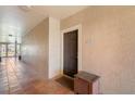 Hallway leading to condo featuring tile floor, dark door, and wooden storage container at 5578 Metrowest Blvd # 310, Orlando, FL 32811