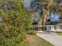 Charming single-story home featuring a blue front door, lush landscaping, and beautiful trees draped in Spanish moss at 719 Se 24Th St, Ocala, FL 34471
