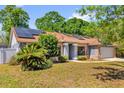 Inviting one-story home with brick accents, solar panels, lush landscaping, and a driveway at 10400 Hunters Trail Ct, Orlando, FL 32817