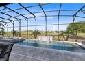 A gorgeous screened pool and spa with a rock waterfall feature overlooking the green golf course at 13349 Alderley Dr, Orlando, FL 32832