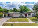 Charming single-story home featuring a well-manicured lawn, carport, and inviting red front door at 1633 Colton, Orlando, FL 32822