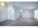 Bright living room with gray carpet, an archway, and modern chandeliers creating an inviting atmosphere at 3199 Quail Dr, Deltona, FL 32738