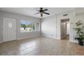 Bright living room with neutral tile flooring, a ceiling fan, and a large window offering natural light at 3214 Debbie Dr, Orlando, FL 32806
