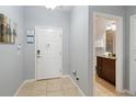 Inviting entryway with a white door, tile floor, and artwork leads to a modern bathroom at 8963 Majesty Palm Rd, Kissimmee, FL 34747