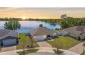 An aerial view showcases the house's proximity to a serene lake, with a well-maintained yard and a brick driveway at 130 Islabella Way, Groveland, FL 34736