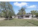 Charming single-story home featuring a manicured lawn, freshly painted white exterior, and beautiful palm trees at 211 Agua Vista St, Debary, FL 32713