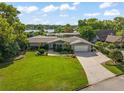 Charming one-story home featuring lush landscaping, a spacious driveway, and a picturesque lake view at 2922 Carmia Dr, Orlando, FL 32806