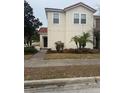 Welcoming home exterior with tan stucco walls, red tile roof, mature landscaping, and a paved walkway to front door at 4573 Ada Ln, Kissimmee, FL 34746