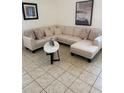 Comfortable living room featuring a sectional sofa, oval coffee table and neutral decor on tile flooring at 4573 Ada Ln, Kissimmee, FL 34746