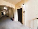 Hallway featuring arched entryways, beige textured walls, carpeted floor, and a dark wood entry door with a '1218' sign at 8276 Maritime Flag St # 201, Windermere, FL 34786