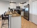 Modern kitchen featuring stainless steel appliances, granite countertops, and a breakfast bar with seating at 8908 Azalea Sands Ln, Davenport, FL 33896