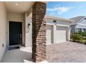 Close-up of a home's exterior showcasing the stone pillar, front door, and brick driveway at 1807 Good Neighbor Loop, Kissimmee, FL 34744