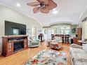 Open living room features vaulted ceilings, wood floors, a fireplace, and bar seating looking into the kitchen at 2124 Westchester Way, The Villages, FL 32162