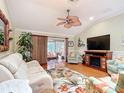 Cozy living room with hardwood floors, a fireplace, a fan and a doorway to a sunroom at 2124 Westchester Way, The Villages, FL 32162