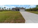 Single-story home with a well-maintained lawn and a long driveway leading to a two-car garage at 23810 Sw Indian Hill Dr, Dunnellon, FL 34431