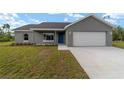 Single-story home with a gray exterior, a blue front door, and an attached two-car garage at 23810 Sw Indian Hill Dr, Dunnellon, FL 34431