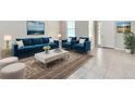 Bright living room with blue sofa, two chairs, plush rug, and lots of natural light at 3954 Great Smokey Way, Apopka, FL 32712