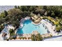 Aerial view of a luxury pool with palm trees, lounge chairs, and a mini golf area overlooking a lake at 482 Captiva Dr, Davenport, FL 33836