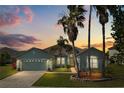 Charming home with a two-car garage, manicured lawn, and mature palm trees at dusk at 5335 Coral Vine Ln, Kissimmee, FL 34758