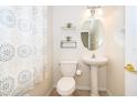 Clean half bath features a pedestal sink, stylish faucet, overhead lighting, toilet, and a decorative mirror at 6274 Bristol Channel Way, Orlando, FL 32829
