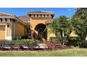 Stunning front entrance with an arched entryway, complemented by lush landscaping and decorative shrubbery at 801 San Raphael St, Poinciana, FL 34759