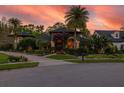 Home exterior showcasing the landscaped yard, mature palm trees, and inviting facade at sunset at 115 Ellington Pl, Oviedo, FL 32765