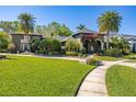 A charming front yard with manicured lawn, palm trees, and brick pathway leading to a home's entrance at 115 Ellington Pl, Oviedo, FL 32765