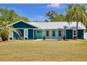 Beautiful blue home with white metal roof and accent trim, plus lush green grass in the front yard at 245 Country Circle E Dr, Port Orange, FL 32128