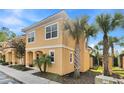 This angle shot shows the 2-story home with tan stucco, tile roof, and lush palm tree at 2608 Roadster Ln, Kissimmee, FL 34746